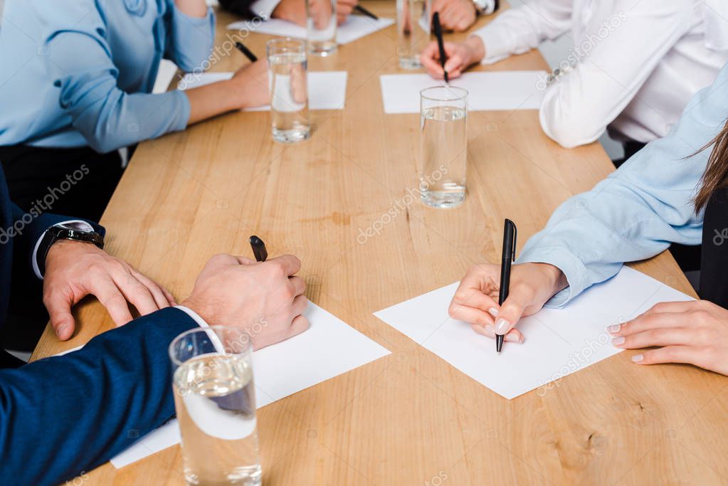 Gruppo di lavoro che discute e scrive documenti su un tavolo